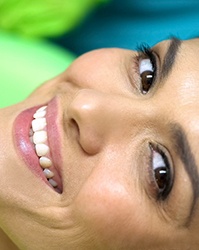 Woman in dental chair smiling with porcelain veneers in Boston