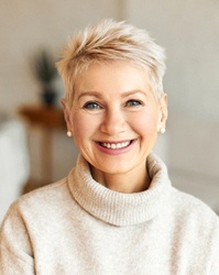 Older woman in sweater in her house smiling