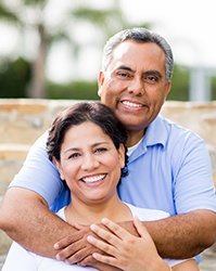 Couple with dental implants in Boston smiling together outside