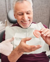 A dentist showing dentures to a senior patient