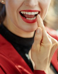 Woman checking teeth after visiting emergency dentist in Boston, MA