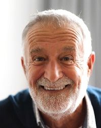 Older man with implant dentures sitting and smiling