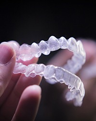 Close-up of hand holding pair of Invisalign aligners