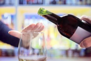 Woman’s hand covering glass to reject more wine