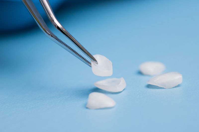 Veneers on a blue surface, one being picked up