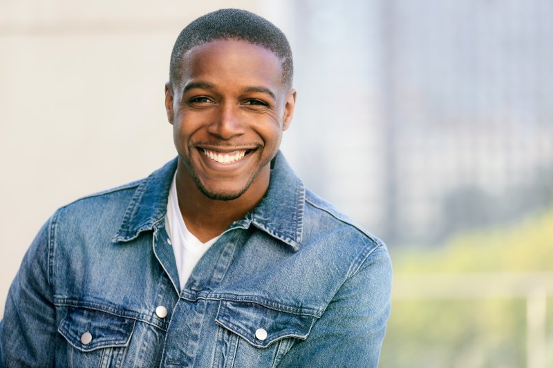 Man in denim jacket outside and smiling