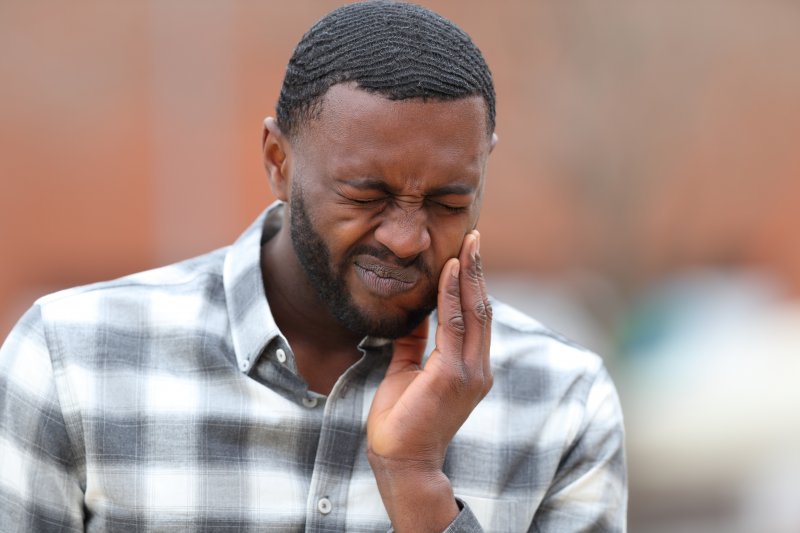 Man in a checkered shirt rubbing jaw