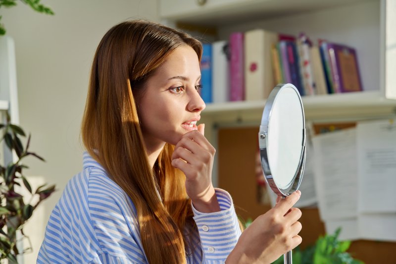 Patient smiling in mirror after dental bonding