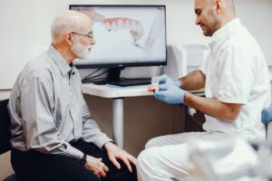Dentist talking with patient while holding dentures.